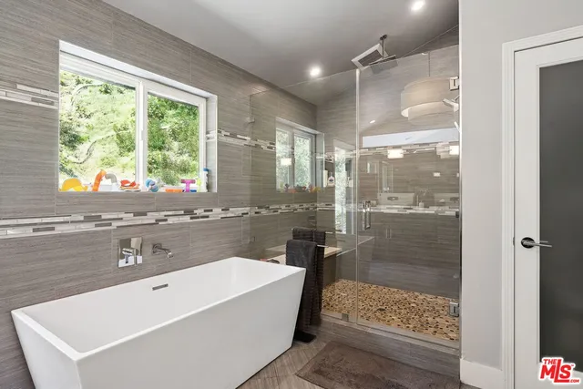 a bathroom with a tub a sink and a large mirror next to a window