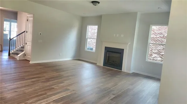 an empty room with wooden floor fireplace and windows