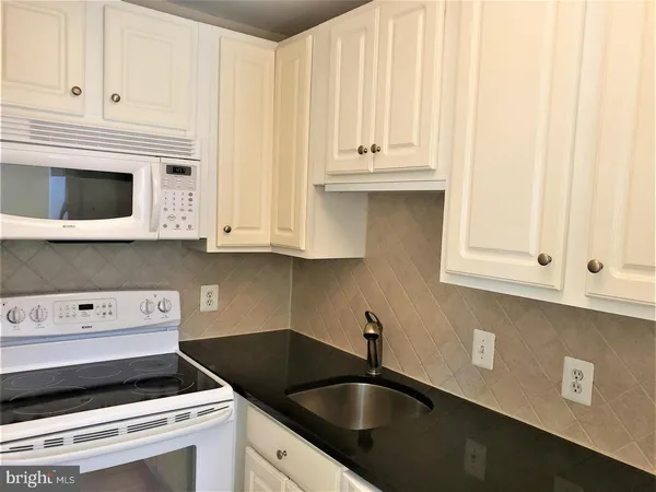 a kitchen with granite countertop white cabinets and black appliances