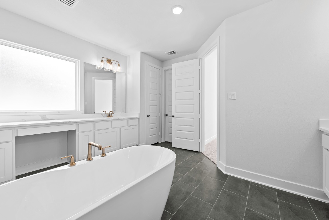 128 Meadow Beauty Lane Georgetown, TX 78633 - Photo 13 of 23 a spacious bathroom with a double vanity sink a mirror and a bathtub