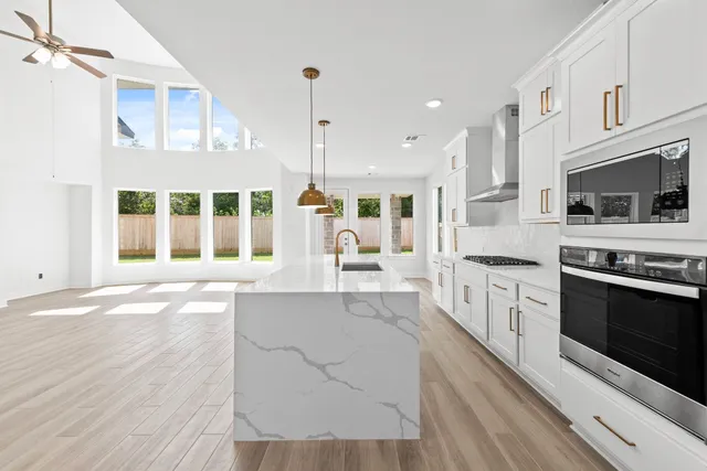 a large kitchen with kitchen island a stove a sink dishwasher a oven with white cabinets and wooden floor