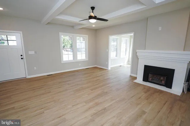 a view of a livingroom with a fireplace wooden floor and windows