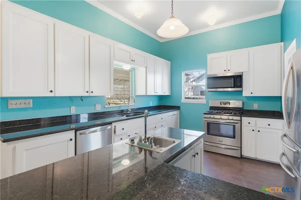 a kitchen with granite countertop a stove a sink and a refrigerator