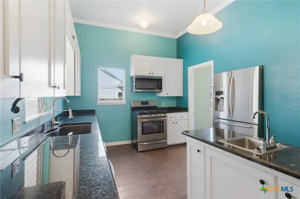 a kitchen with granite countertop a refrigerator stove and sink