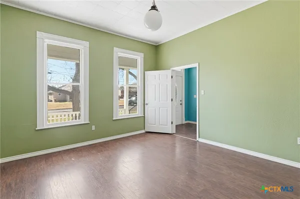 an empty room with wooden floor and windows