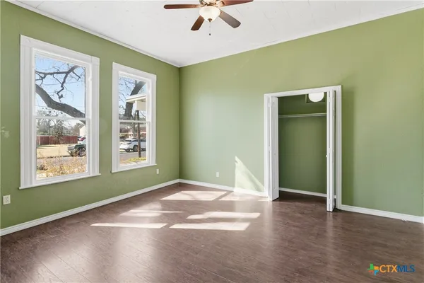 a view of an empty room with a window and wooden floor