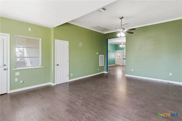 a view of an empty room with window and wooden floor