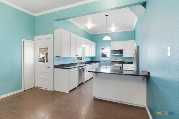 a kitchen with stainless steel appliances a refrigerator a sink dishwasher a stove and white cabinets