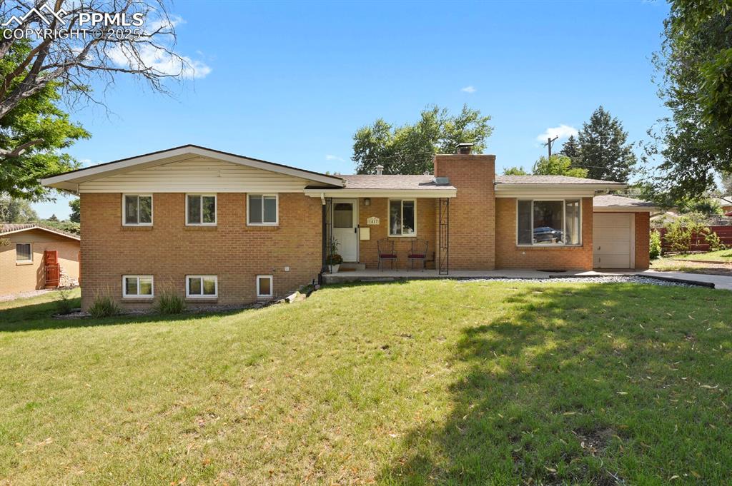 1417 Prairie Road Colorado Springs, CO 80909 - Photo 1 of 34 a front view of a house with a garden