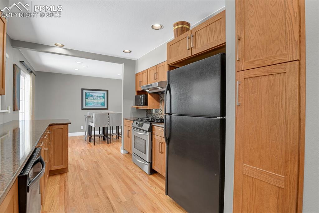1417 Prairie Road Colorado Springs, CO 80909 - Photo 11 of 34 a kitchen with stainless steel appliances granite countertop a refrigerator a stove and a dining table with wooden floor