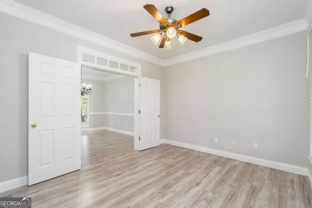 an empty room with wooden floor and a ceiling fan