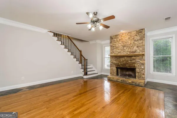 a view of an empty room with wooden floor fireplace and a window