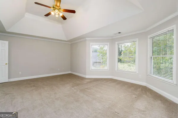 an empty room with windows and fan