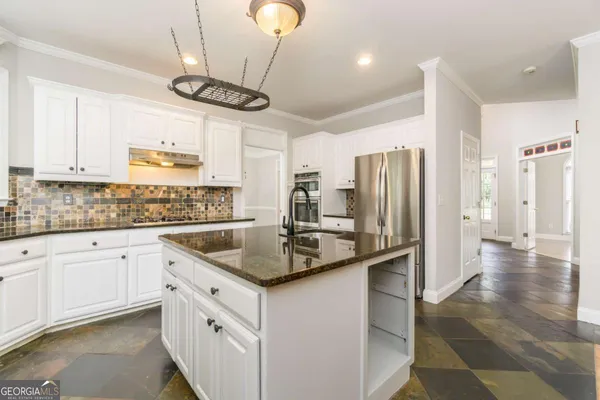 a kitchen with stainless steel appliances granite countertop a sink a stove a refrigerator and island with wooden floor