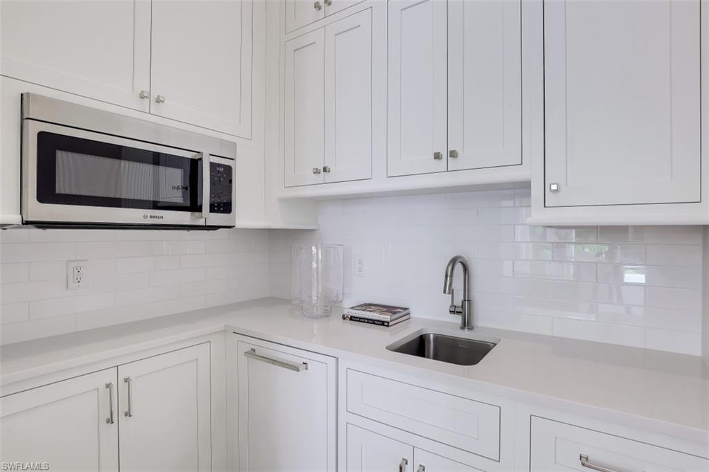 650 Wedge Drive Naples, FL 34103 - Photo 27 of 34 a kitchen with white cabinets and stainless steel appliances