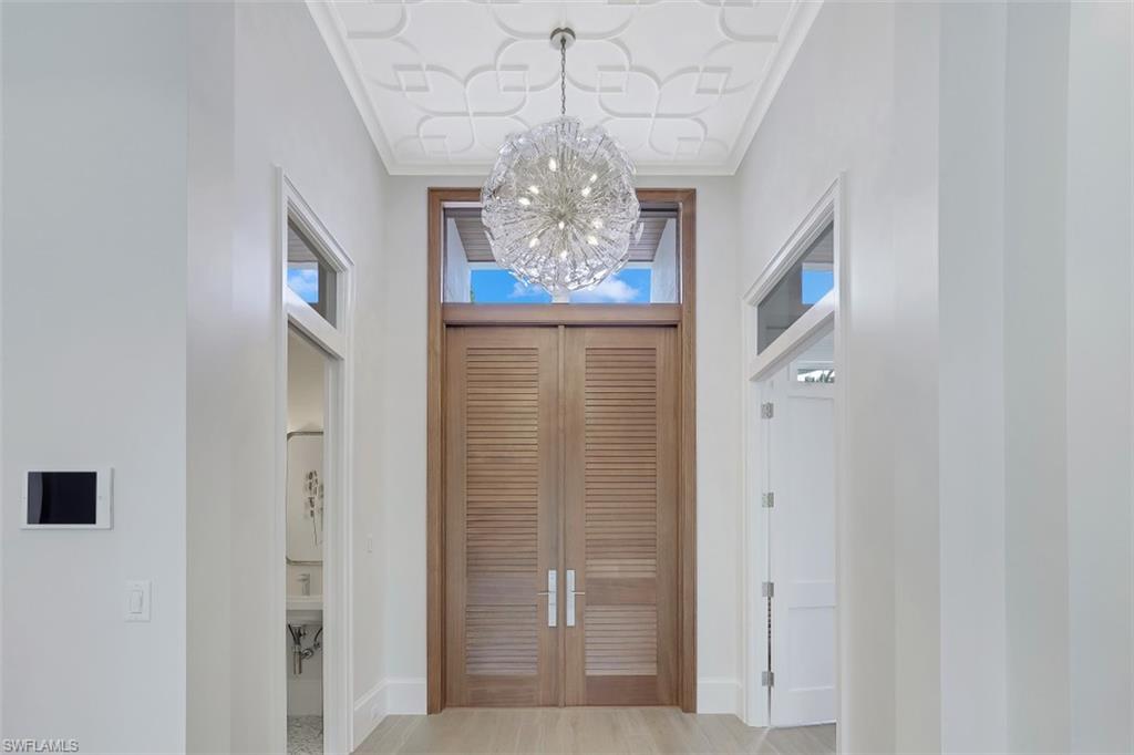 650 Wedge Drive Naples, FL 34103 - Photo 6 of 34 a view of a hallway with chandelier and door