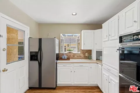 a kitchen with white cabinets and refrigerator
