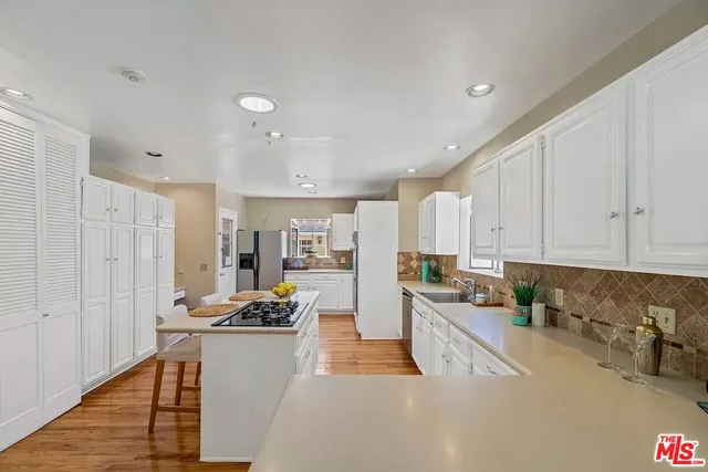 a kitchen with stainless steel appliances a stove a sink a refrigerator a center island and cabinets