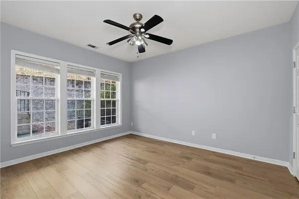 a view of an empty room with wooden floor and a window