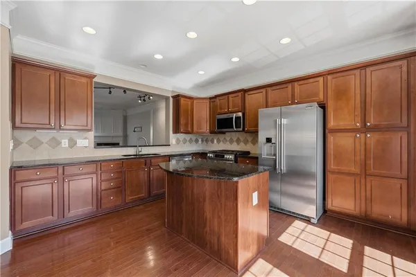 a kitchen with granite countertop stainless steel appliances a refrigerator a sink and cabinets
