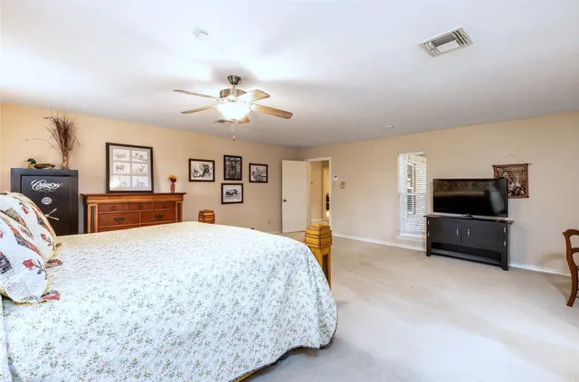 a spacious bedroom with a bed a dresser and a flat screen tv