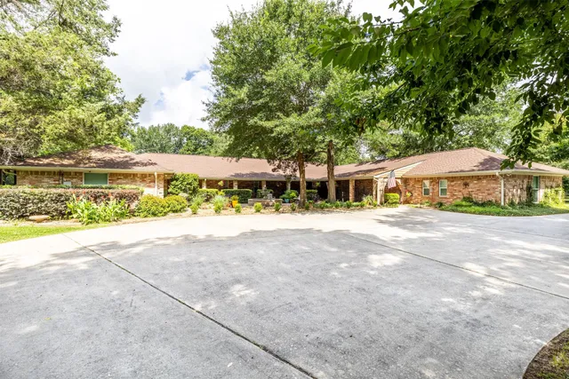 a front view of a house with a yard and a large tree