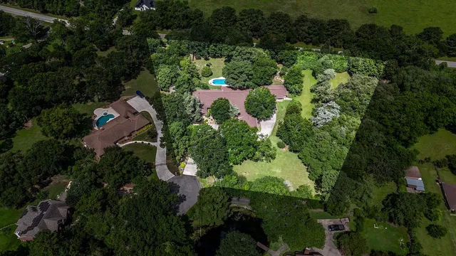 an aerial view of residential house with outdoor space and trees all around