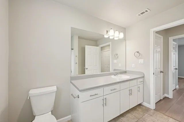 a spacious bathroom with a toilet a sink and mirror