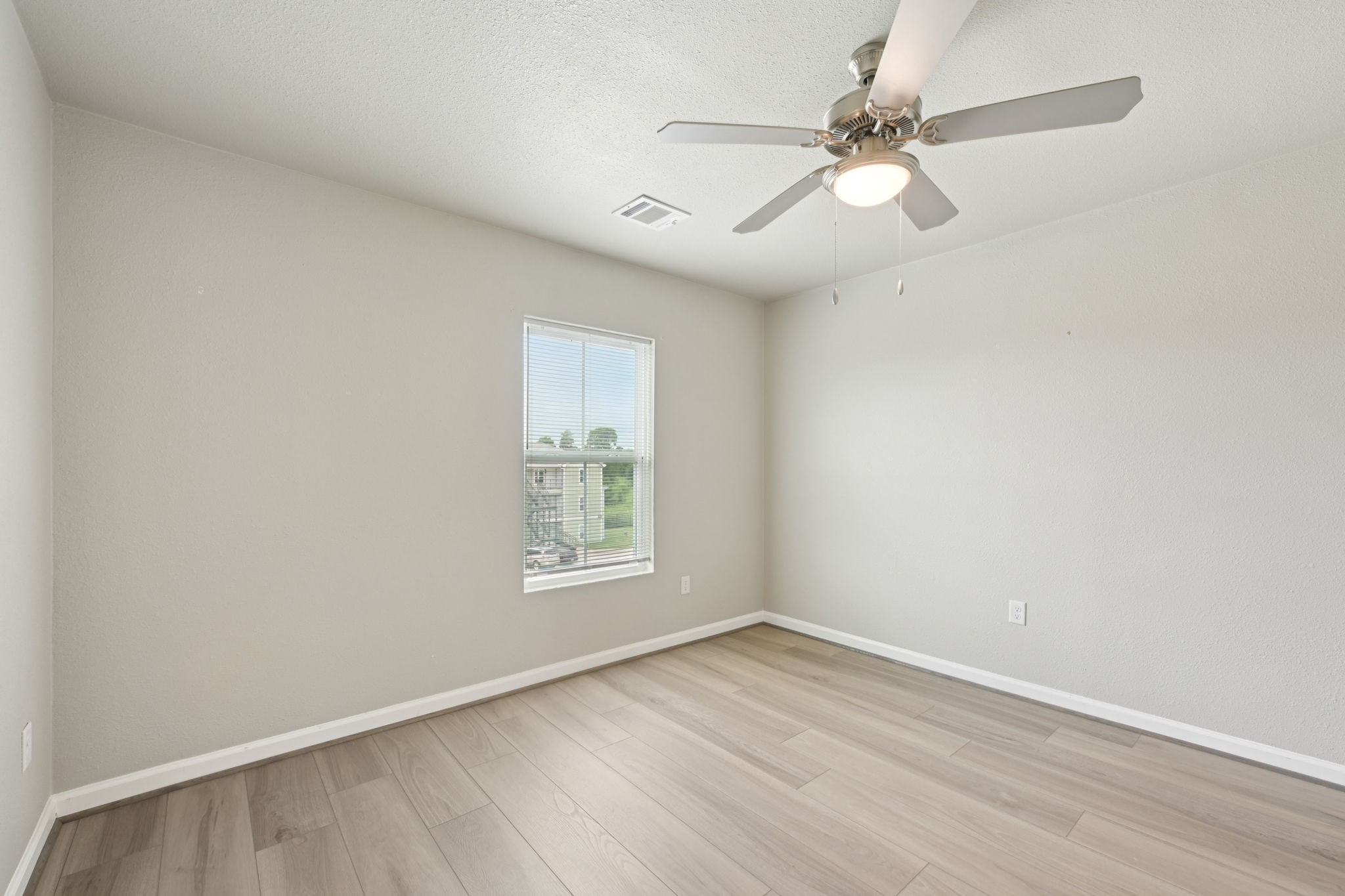 254 Plez Morgan Drive, Unit F Montgomery, TX 77356 - Photo 24 of 31 an empty room with wooden floor fan and windows