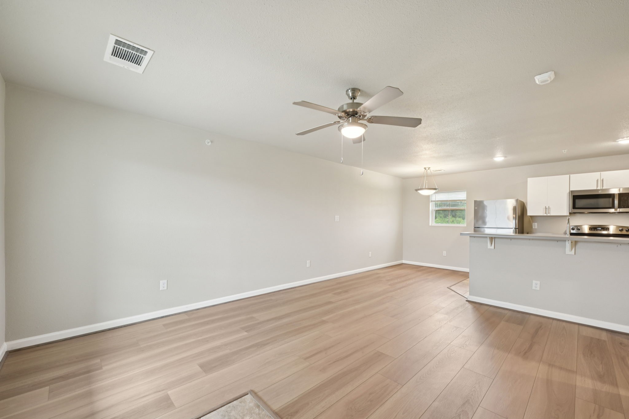 254 Plez Morgan Drive, Unit F Montgomery, TX 77356 - Photo 5 of 31 an empty room with wooden floor and a ceiling fan