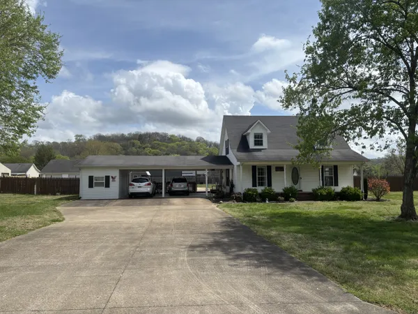 a view of a house with a big yard and large trees