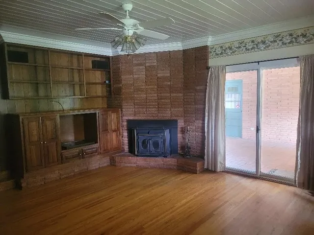 a view of an empty room with wooden floor fireplace and a window