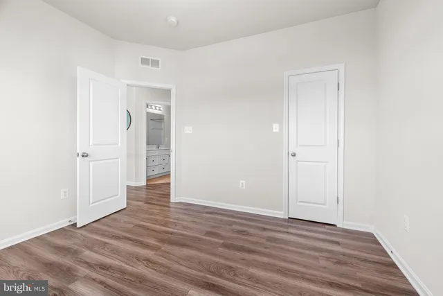 a view of an empty room with wooden floor and closet