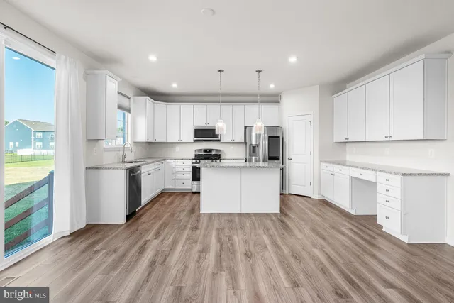 a kitchen with stainless steel appliances granite countertop a refrigerator a stove top oven a sink dishwasher and white cabinets with wooden floor