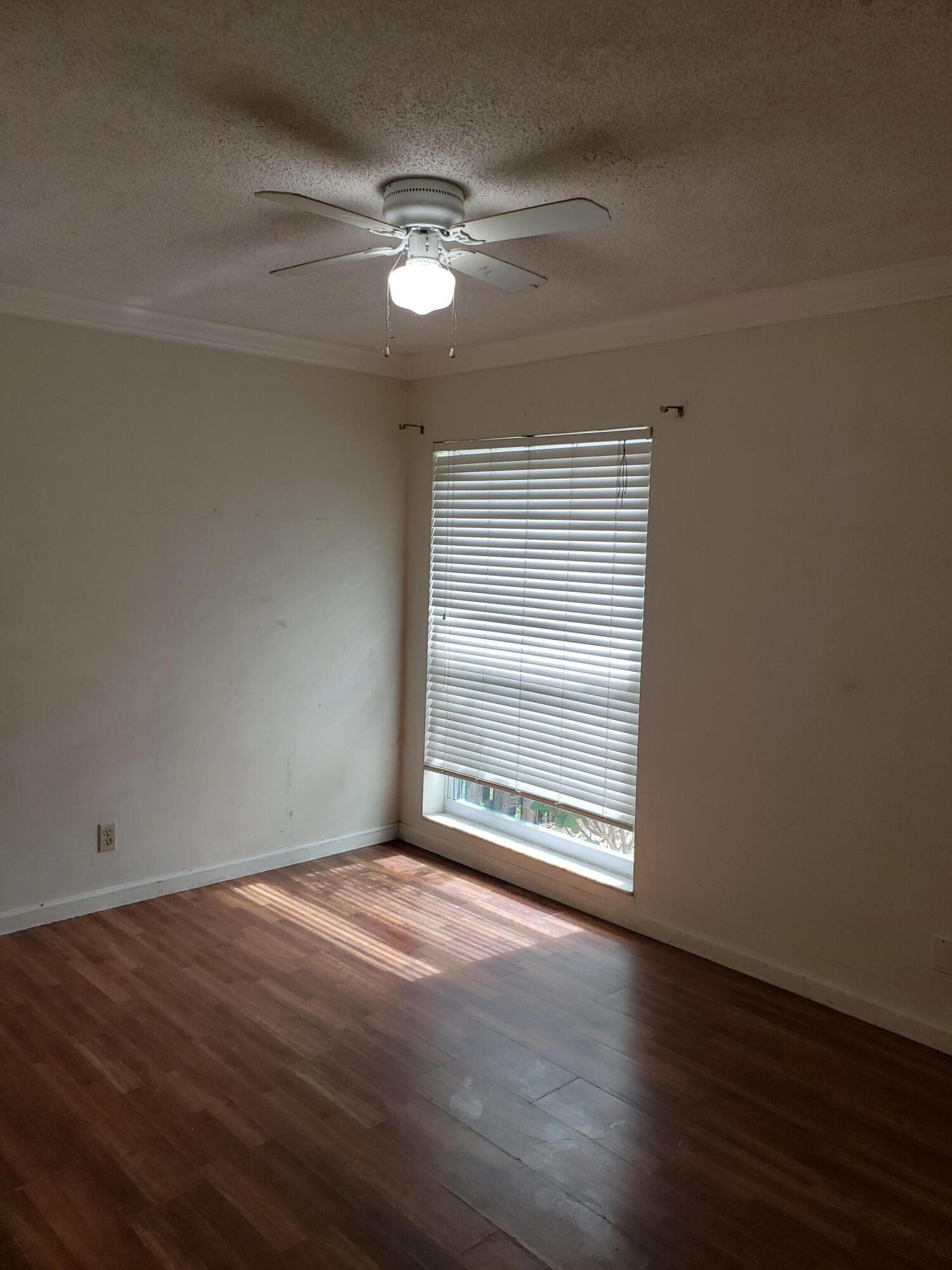 5673 Biscayne Drive Greenacres, FL 33463 - Photo 19 of 24 a view of an empty room with wooden floor and a window