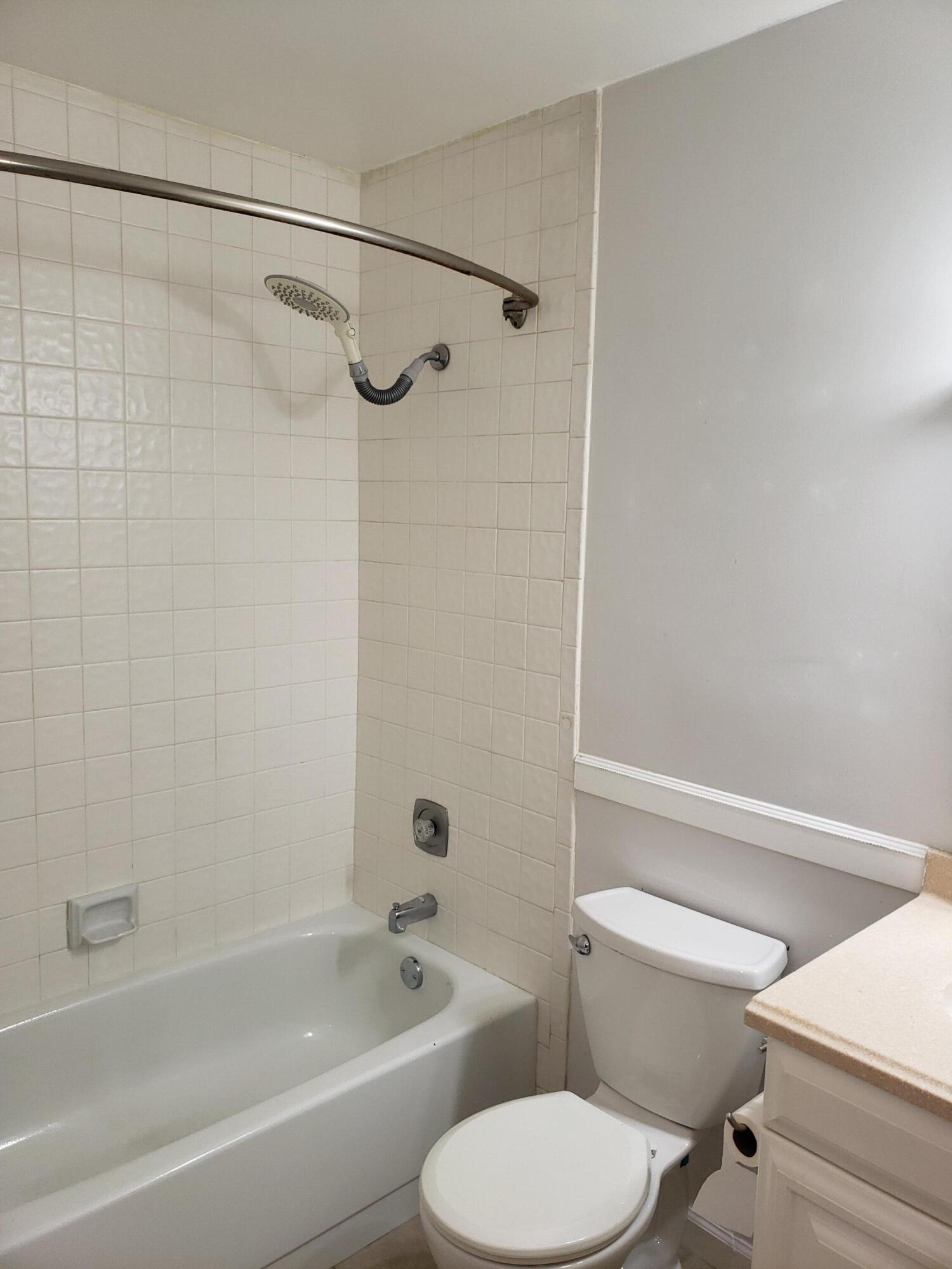 5673 Biscayne Drive Greenacres, FL 33463 - Photo 21 of 24 a white toilet and tub sitting next to a bathroom sink