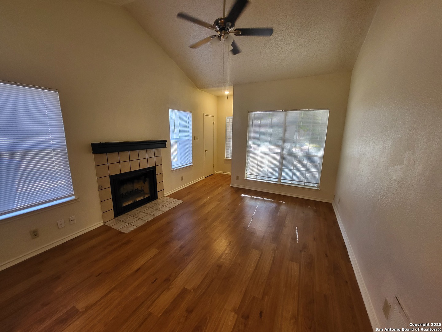 3405 Ridge Smoke San Antonio, TX 78247 - Photo 3 of 16 an empty room with wooden floor fireplace and windows