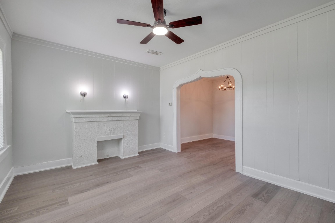 7406 Bethune Avenue Austin, TX 78752 - Photo 18 of 38 an empty room with wooden floor a ceiling fan a fireplace and windows
