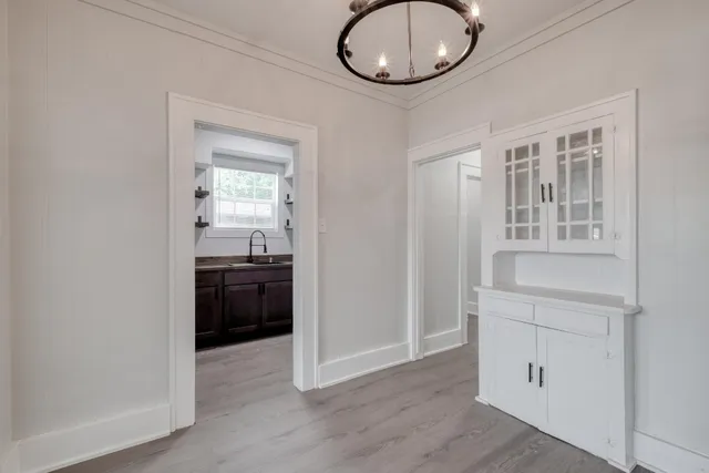 an empty room with wooden floor cabinet and windows