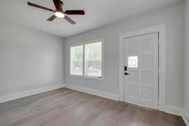 a view of empty room with wooden floor and fan