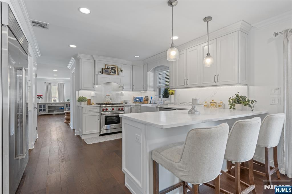 11 Robin Hood Way Wayne, NJ 07470 - Photo 14 of 36 a kitchen with kitchen island granite countertop a dining table chairs refrigerator and white cabinets