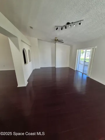 a view of an empty room with wooden floor and windows