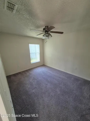 an empty room with windows and ceiling fan view