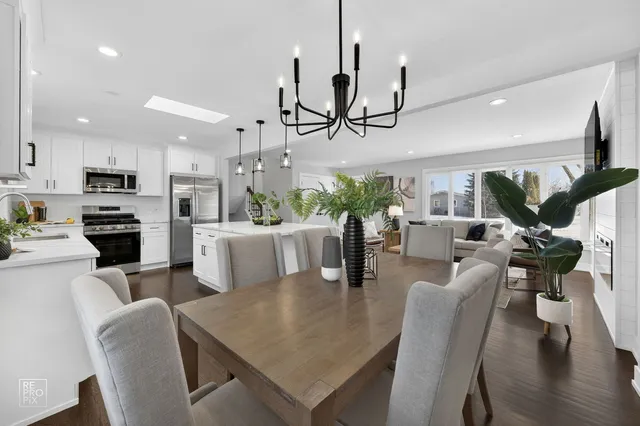 a view of a dining room and livingroom with furniture wooden floor a chandelier