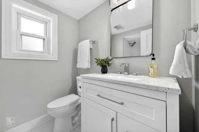a bathroom with a granite countertop sink toilet and mirror