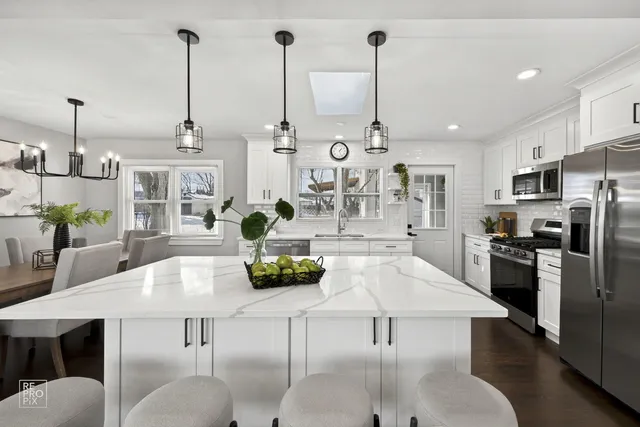 a kitchen with stainless steel appliances kitchen island granite countertop a table a stove and a chandelier