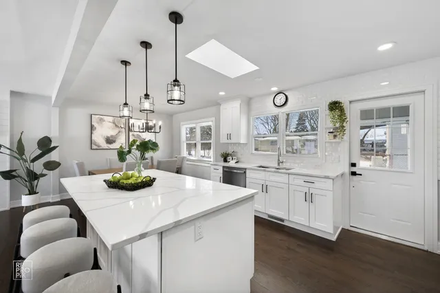 a kitchen with stainless steel appliances kitchen island granite countertop a white cabinets a stove and a wooden floor
