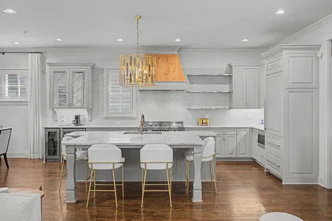 a kitchen with a sink stove and white cabinets with wooden floor