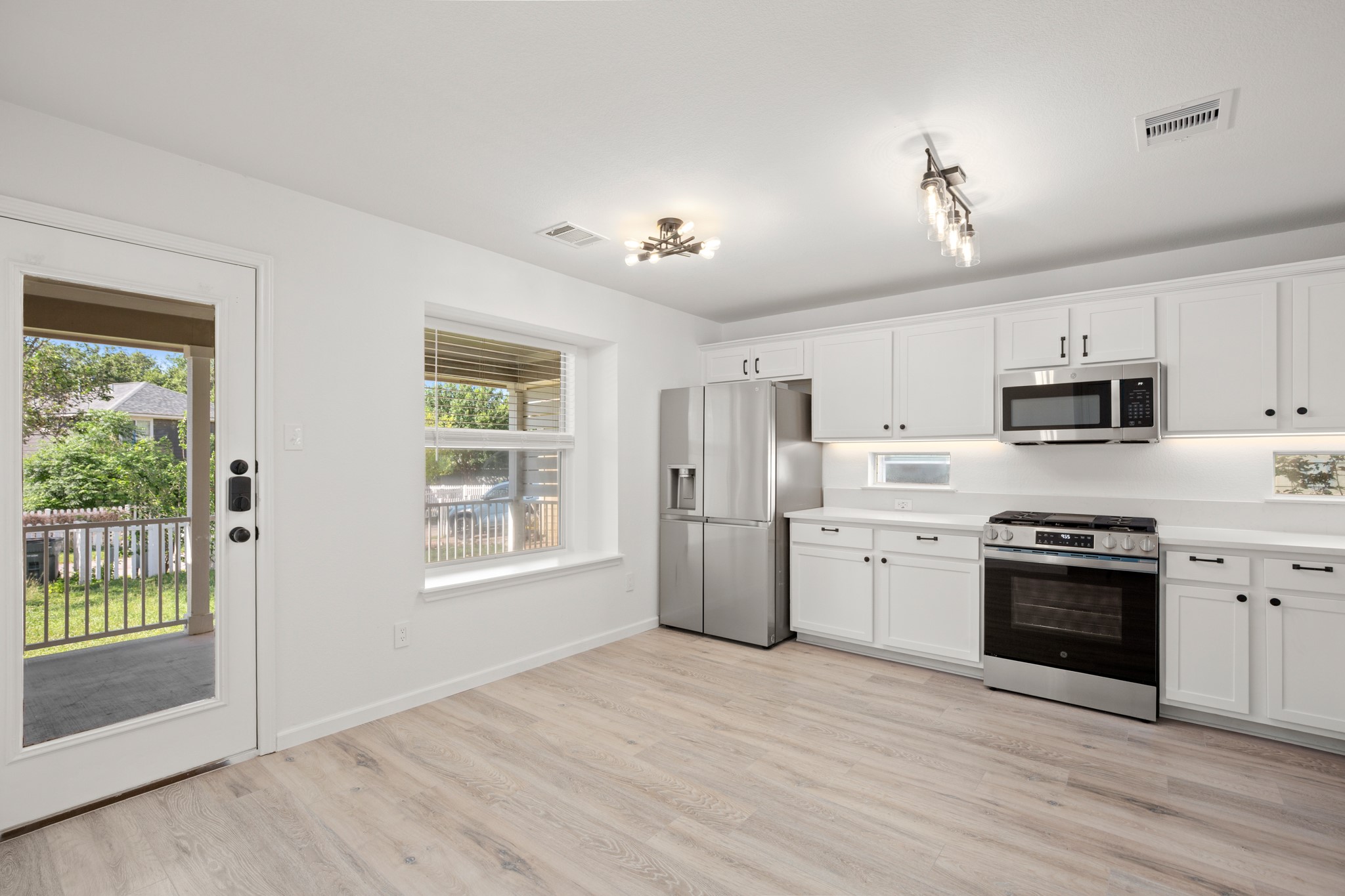 360 Sampson Kyle, TX 78640 - Photo 7 of 36 Bright kitchen featuring white quartz countertops, white cabinetry, stainless steel appliances, light wood-finish flooring, and a contemporary ceiling fixture