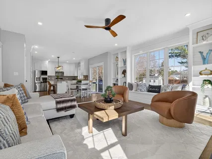 a living room with furniture kitchen view and a large window